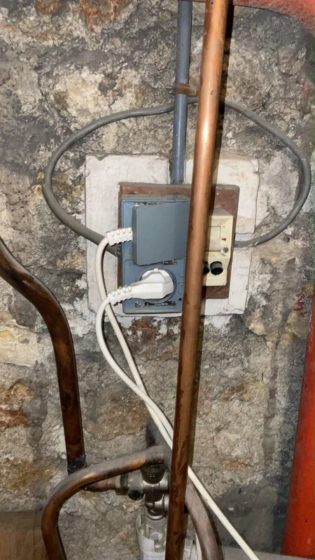 Prise et boîtier électriques vétustes sur mur en pierre